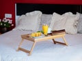 Breakfast served in bed on a wooden tray with tea, juice, cookies. Hotel room service, relax concept Royalty Free Stock Photo