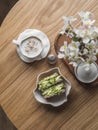 Breakfast served, brunch table - cappuccino and avocado, eggs, micro greens toast on a round wooden table, top view. Aesthetic