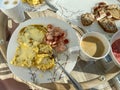 Breakfast is served on a light board. Fried eggs, omelet, croissant, coffee, dessert, place for text. In the hands of a fork and a Royalty Free Stock Photo