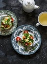 Breakfast served - sandwiches with egg, avocado, micro-greenery and green tea on a dark background, top view Royalty Free Stock Photo