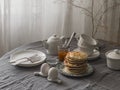 Breakfast served on the table - pancakes, apricot jam, boiled eggs in ceramic egg stands, breakfast dishes on the table with a