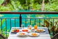 Breakfast served on terrace in outdoors restaurant at luxury tropical hotel or resort. Brunch table with food and drinks