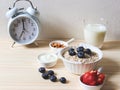 Breakfast set, oat or granola in white bowl, fresh blueberries and strawberries, a  glass of milk and white vintage alarm clock 7 Royalty Free Stock Photo