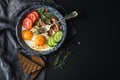 Breakfast set. Pan of fried eggs with bacon, fresh tomato, cucumber, sage and bread on dark serving board over black Royalty Free Stock Photo