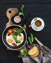 Breakfast set. Pan of fried eggs, bacon, tomatoes with bread, mangold and cucumbers, coffee on rustic wooden serving Royalty Free Stock Photo