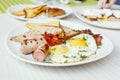 Breakfast setting with fried eggs, bacon, muesli, croissants and juice. Royalty Free Stock Photo