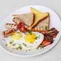 Breakfast setting with fried eggs, bacon, muesli, croissants and juice. Royalty Free Stock Photo