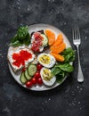 Breakfast, snack, tapas plate - sandwiches with red caviar, salmon, cream cheese, vegetables, spinach, boiled egg on a dark Royalty Free Stock Photo