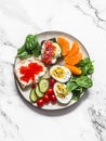 Breakfast, snack, tapas plate - sandwiches with red caviar, salmon, cream cheese, vegetables, spinach, boiled egg on a light Royalty Free Stock Photo