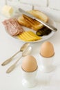 Breakfast with soft-boiled egg, bread toast, ham, cheese and canned cucumbers. Rustic style.