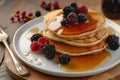 breakfast spread with pancakes, syrup, and berries