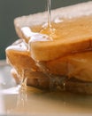 Honey dripping from a glass on white bread close-up