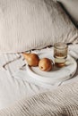 Breakfast still life composition. Glass of water, newspapers and pear fruit on white marble tray. White linen background