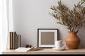 Breakfast still life. Cup of coffee, books and empty picture frame mockup on wooden desk, table. Vase with olive