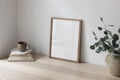 Breakfast still life. Cup of coffee, books. Empty wooden picture frame mockup on desk, table. Textured vase with silver Royalty Free Stock Photo