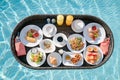 Breakfast in swimming pool, floating breakfast set in tray in resort