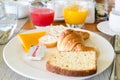 Breakfast on table in cafe with juice, croissant, cake on plate