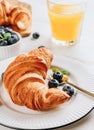 Breakfast table with croissants, coffee, orange juice and blueberries Royalty Free Stock Photo