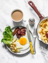 Breakfast table - fried egg, bacon, green salad, hash potatoes and coffee with cream on a light marble background, top view Royalty Free Stock Photo