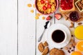 Breakfast table with healthy tasty ingredients. Coffee, toast, jam, corn flakes, cookies, almonds, orange juice and fruit on white Royalty Free Stock Photo