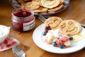 Breakfast table: pancakes, fruit salad, jam, yogurt