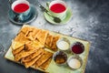 Breakfast on the table with pancakes, sour cream, honey, jam and cup of red tea