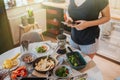 Breakfast table and woman poring coffee holding phone