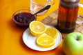 Breakfast tea in French press  lemon  cup  jam with spoon  apple  orange background Royalty Free Stock Photo