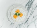 Breakfast is three eggs fried on a white plate on a white marble background.