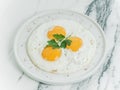 Breakfast is three eggs fried on a white plate on a white marble background