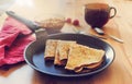 Breakfast: three pancakes in a black pan, buckwheat porridge in a bowl, a dark glass with a drink, a cherry towel, a