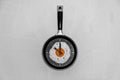 Breakfast time concept fried egg on cooking pan shaped clock on light background