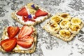 Breakfast with toaster and oat bread, buttered with butter, jam, strawberries and bananas on a concrete table. Royalty Free Stock Photo