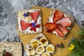 Breakfast with toaster and oat bread, buttered with butter, jam, strawberries and bananas on a concrete table Royalty Free Stock Photo