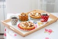 Breakfast tray with pancakes with bananas, maple syrup and nuts, cup of coffee and honey