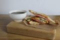 Breakfast on a tray of sandwiches with ham cheese greens on a wooden tray next to a cup of coffee tea. Breakfast to the room.