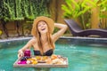 Breakfast tray in swimming pool, floating breakfast in luxury hotel. Girl relaxing in the pool drinking smoothies and Royalty Free Stock Photo