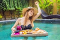 Breakfast tray in swimming pool, floating breakfast in luxury hotel. Girl relaxing in the pool drinking smoothies and Royalty Free Stock Photo