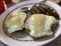 Two eggs with cheese over toast with sausage links