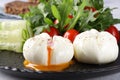 Breakfast with two poached eggs with flowing yolk, with arugula salad,cucumbers and cherry tomatoes, on a black plate Royalty Free Stock Photo