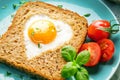 Breakfast on Valentine`s Day - fried eggs and bread in the shape of a heart and fresh vegetables Royalty Free Stock Photo