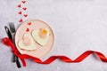 Breakfast on Valentine`s Day - fried eggs on pink plate and red hearts on grey stone background. Top view, copy space