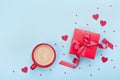 Breakfast for Valentines day. Coffee, gift box, paper heart and confetti on blue background top view. Empty space for text.