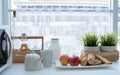 Breakfast in the white kitchen. red apples, loaves of bread, pastry, tea pot, bottle of milk and honey on the table next to window Royalty Free Stock Photo
