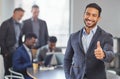 Breaking out my own box. Portrait of a young businessman showing the thumbs up in front of his colleagues having a Royalty Free Stock Photo