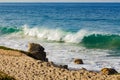 Breaking transparent turquoise wave with backwash and backspray on a sandy beach Royalty Free Stock Photo