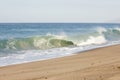 Breaking tube wave on sandy beach with foamy backwash, open expanse of ocean Royalty Free Stock Photo