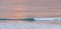 Breaking turquoise ocean wave at sunset.