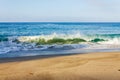 Breaking wave on shoreline with backwash, backspray, with sandy beach Royalty Free Stock Photo