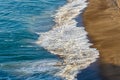 Breaking waves foam spreading on shoreline sand with watching seagull flock Royalty Free Stock Photo